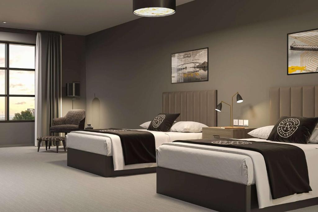 ein Hotelzimmer mit zwei Betten und einem Stuhl in der Unterkunft Riverbend Hotel and Suites, Trademark Collection by Wyndham in Ashtabula
