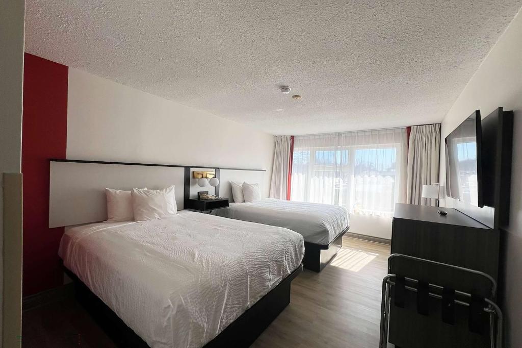 a hotel room with two beds and a window at Ramada by Wyndham Kingston in Kingston
