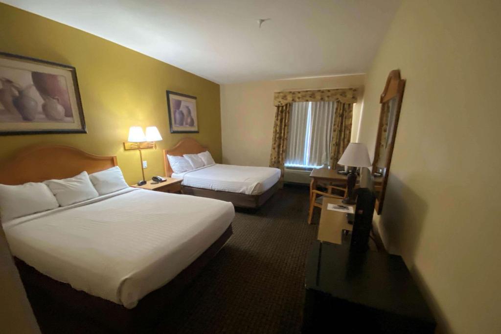 a hotel room with two beds and a desk with a bed and a couch at Tombstone Grand Hotel, a Baymont by Wyndham in Tombstone