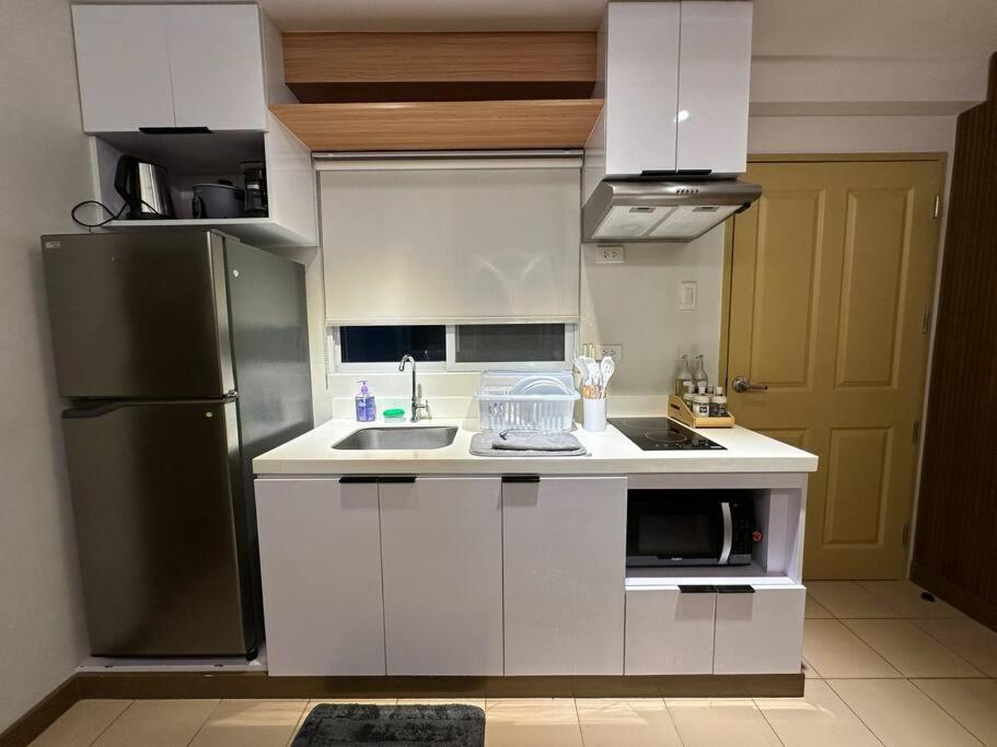 伊洛伊洛的住宿－Cozy 2 Bedroom End Unit，厨房配有白色橱柜和黑色冰箱。