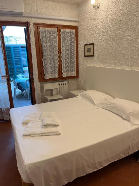 um quarto com uma grande cama branca com toalhas em CASA FELICITINA a pochi passi dal mare em Bonassola