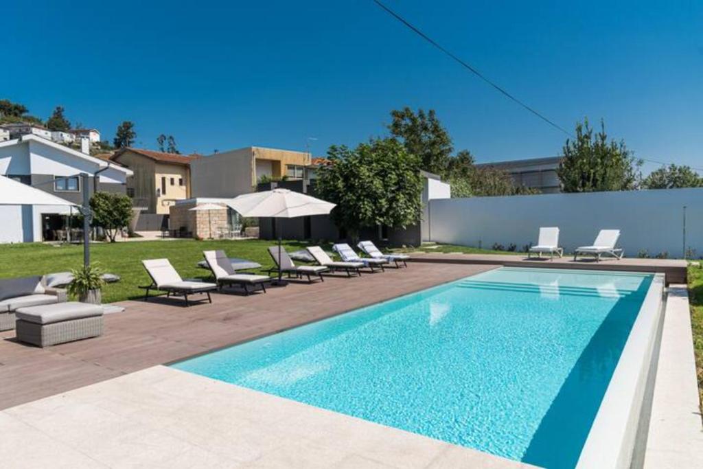 una piscina con sillas y sombrillas en un patio en Casa Pelourinho de Louredo with pool, en Paredes