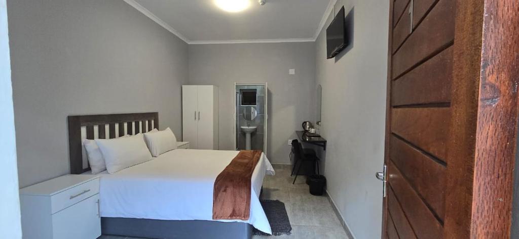 1 dormitorio con cama blanca y puerta de madera en Abay Lodge en Durban