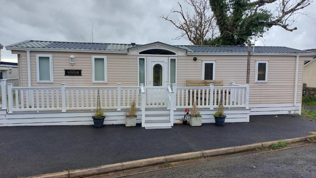a house with a white fence and a porch at 2 bedroom caravan near Llanberis, on the edge of Snowdonia in Llanddeiniolen