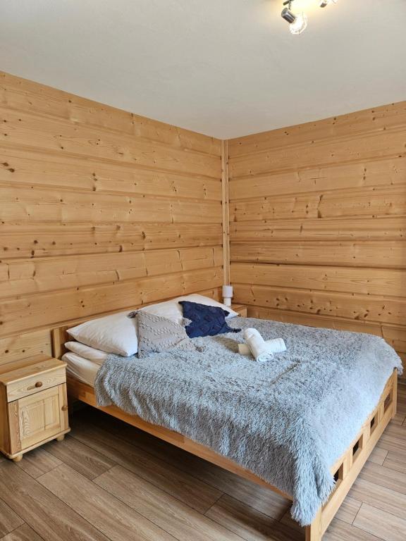 um quarto com uma cama e uma parede de madeira em Apartamenty u Rysulów em Kościelisko