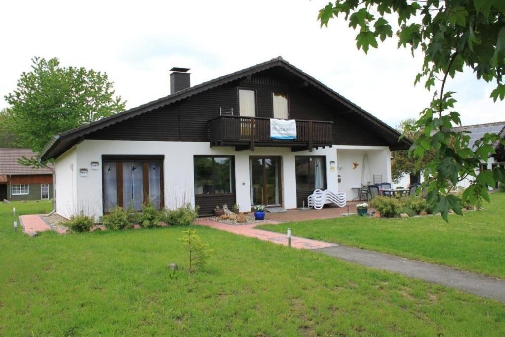 Cette maison blanche dispose d'un balcon et d'une cour. dans l'établissement Ferienhaus in Feriendorf Silbersee mit Garten, Terrasse und Grill, à Frielendorf
