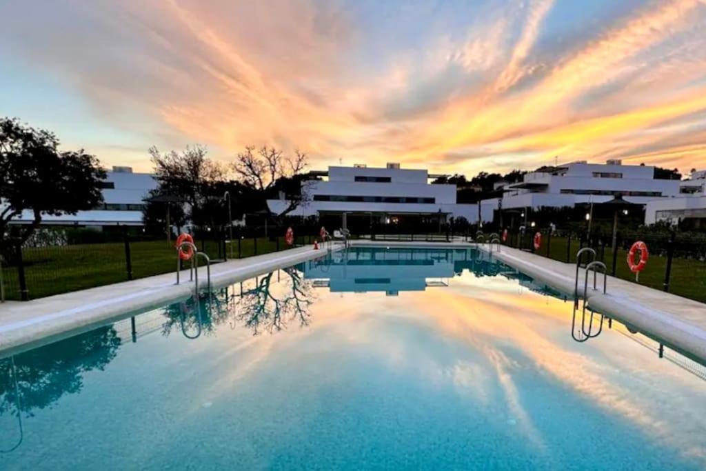 a large swimming pool with a sunset in the background at Spacieux Appartement 3 chambres Reserva Sotogrande in San Roque