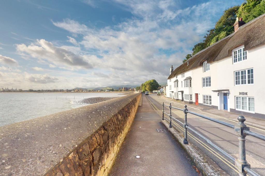 a sidewalk next to a wall next to the water at Captains Cottage Minehead in Minehead
