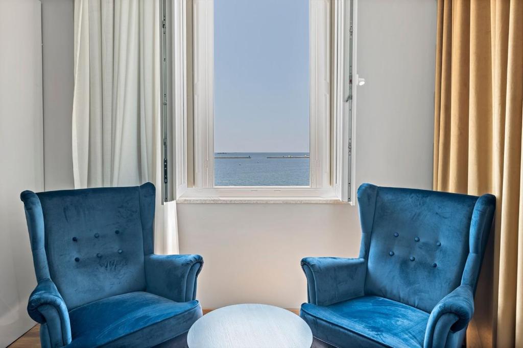two blue chairs and a table in front of a window at Hotel Dua Residence in Poreč
