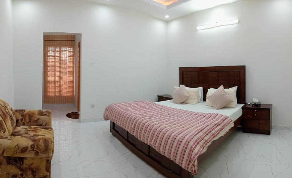 ein Schlafzimmer mit einem großen Bett und einem Stuhl in der Unterkunft Haven Lodge, Bahria Enclave in Islamabad