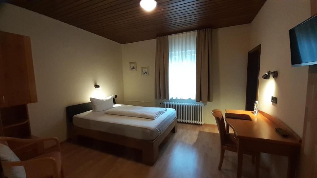 a bedroom with a bed and a desk and a window at Hotel - Gasthof Blume in Oppenau