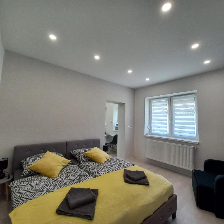 Un dormitorio con una cama con almohadas amarillas y una ventana en Stílus Apartman, en Vásárosnamény