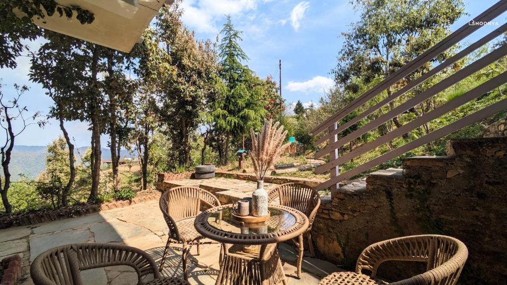 a patio with chairs and a table with a view at Shoonya Mukteshwar in Mukteswar