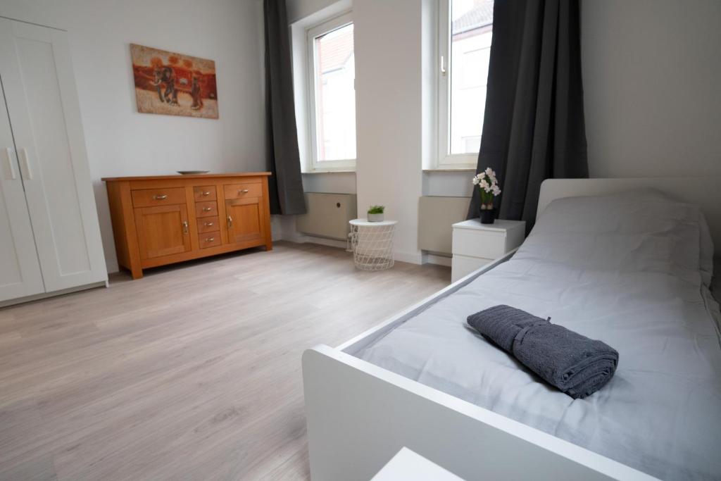 - une chambre avec un lit blanc et une commode en bois dans l'établissement Mieterlux Frankfurt Obertshausen, à Obertshausen