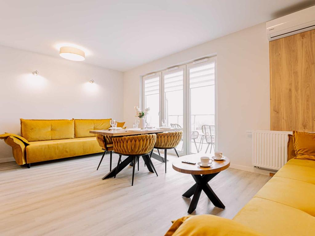 a living room with a table and a yellow couch at VacationClub - Apartamenty Zakopiańskie Apartament 437 in Zakopane