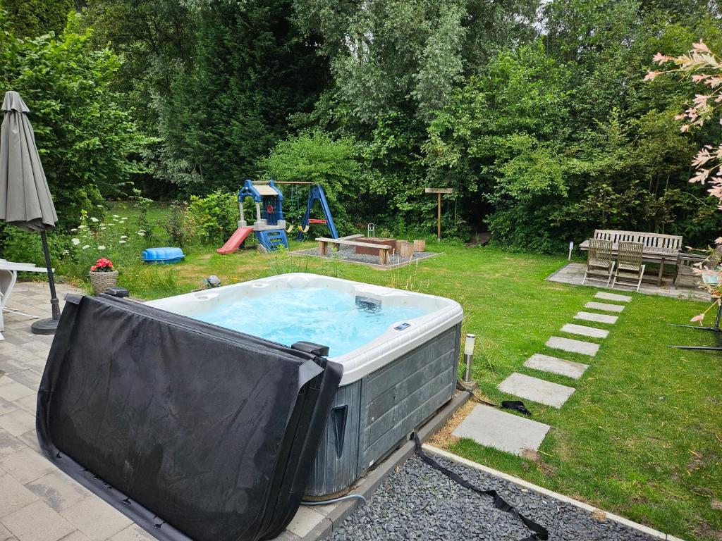 a hot tub in a yard with a playground at Family home, large garden, playground kids, firepit, terraces, sleeps max 7 and 1 babycot, kids playroom inside in Ewijk