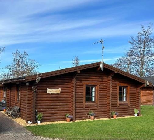 a log cabin with potted plants in front of it at Laura's Lodge Hot Tub Log Cabin, Felmoor Park, Morpeth, Northumberland in Felton