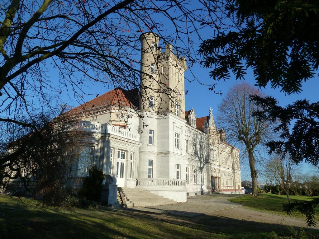 een groot wit kasteel met twee schoorstenen bovenop bij Apartament pałacowy in Świebodzin