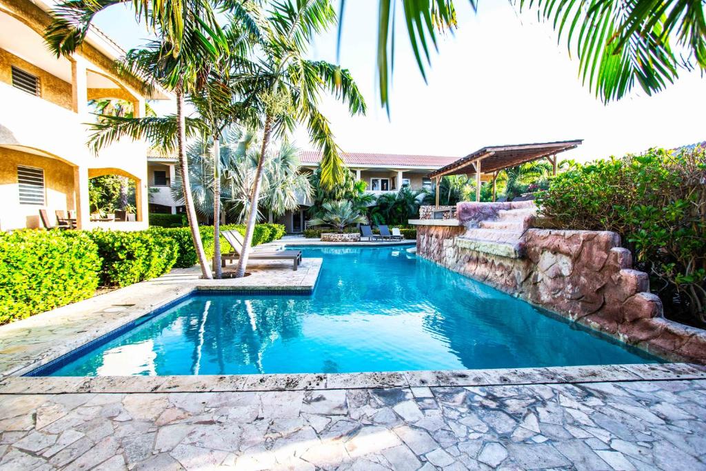 a swimming pool in a backyard with palm trees at CocoCasa 22 Stylish Luxury Apartment with Pool near Jan Thiel Beach in Willemstad