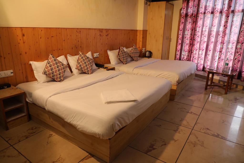 two beds in a room with two windows at Hotel Sita Inn in Shimla