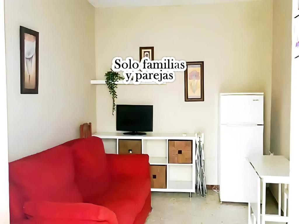 een woonkamer met een rode stoel en een tv bij Apartamento Cerca de la Playa en Conil in Conil de la Frontera