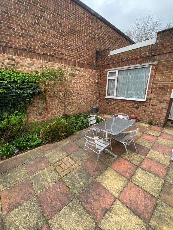 a patio with two chairs and a table in front of a brick building at 62 Sturry Road in Canterbury