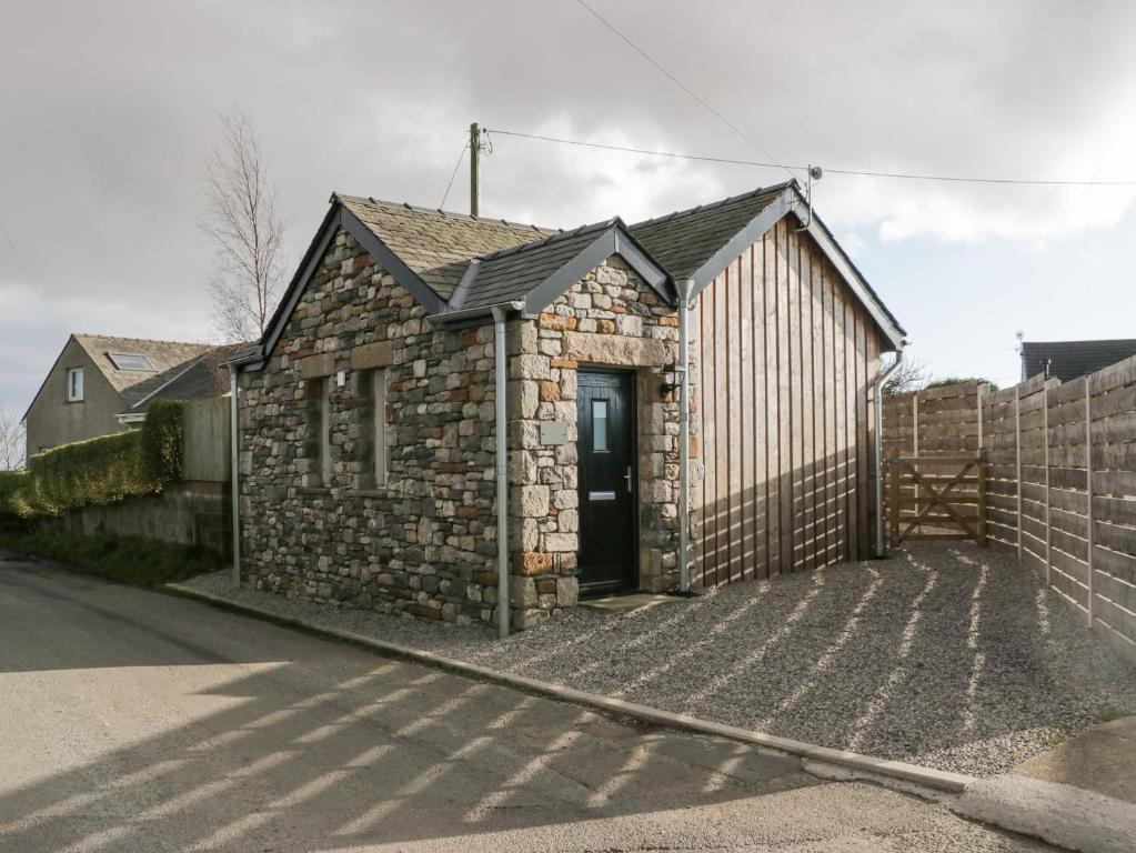 a small stone building with a door on a street at Driftwood Studio in Ulverston