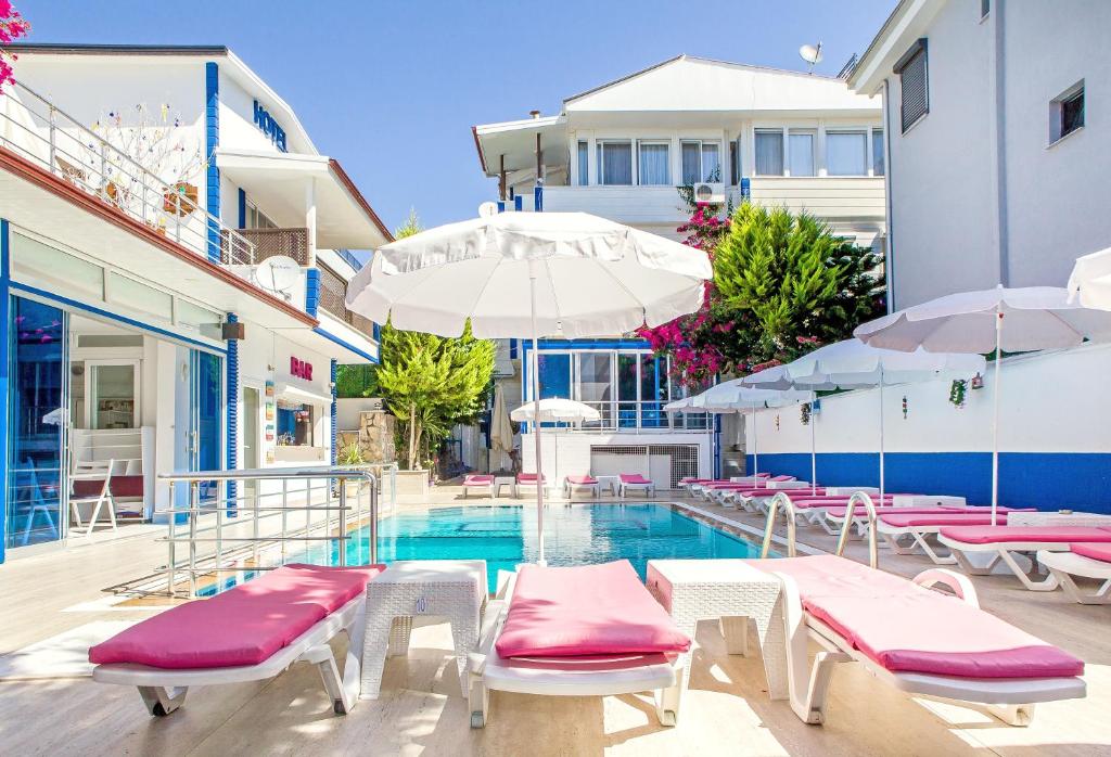 a pool with chairs and umbrellas next to a building at MERVE BUTİK OTEL in Didim