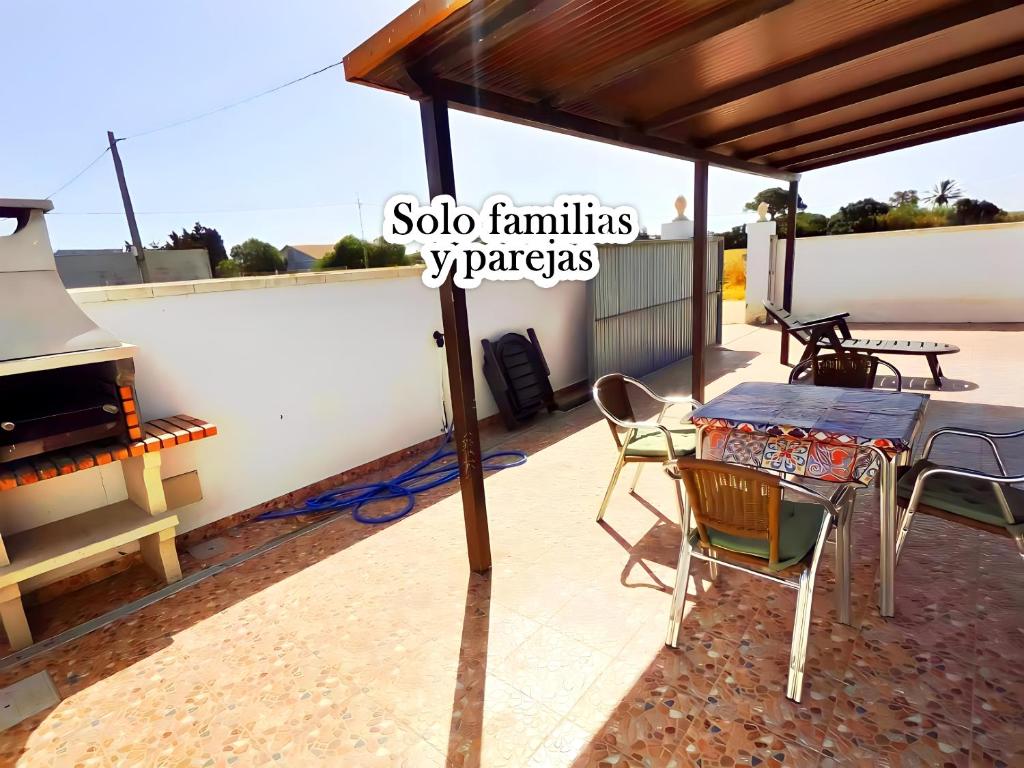 un patio con mesa, sillas y parrilla en Chalet en el Palmar solo familias y parejas, en El Palmar