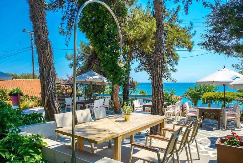 a wooden table and chairs with the ocean in the background at Thassos ESPERIA HOTEL in Pefkari