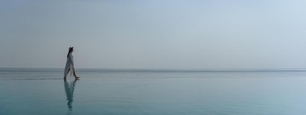 a person standing in the ocean with a sail at Naama Beach Villas & Spa in Al Aqah