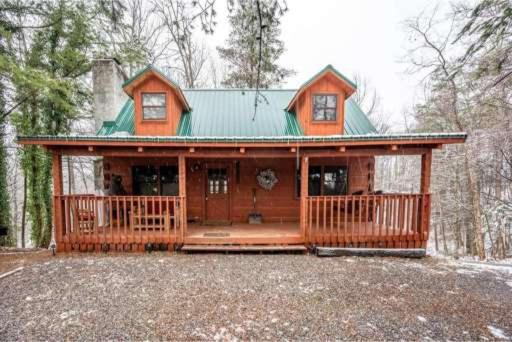 a large wooden house with a green roof at A Charming Cabin, Pool, Firepit, Hot Tub-jacuzzi in Gatlinburg