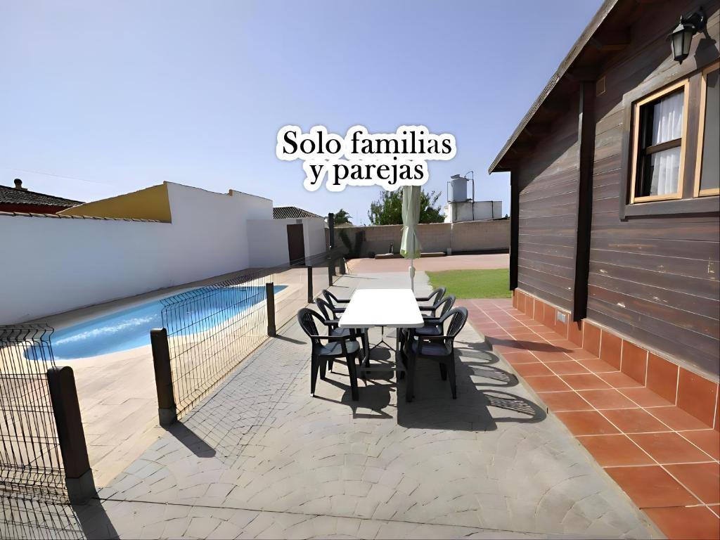 um pátio com uma mesa e cadeiras ao lado de uma piscina em Casa de Madera Piscina Privada en Chiclana em Chiclana de la Frontera