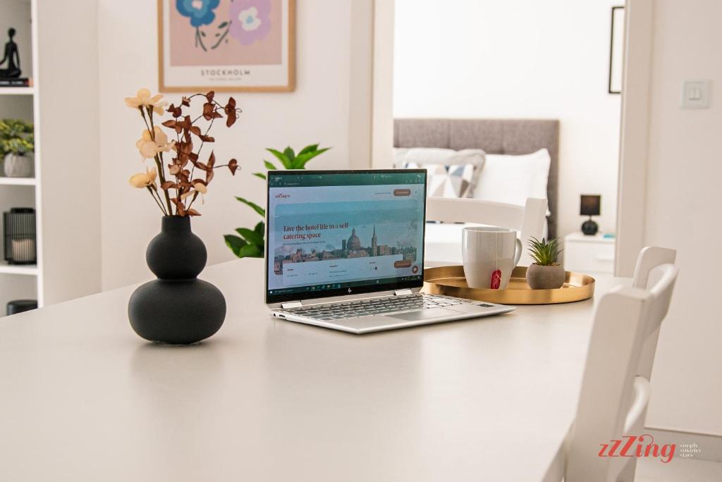 laptopa siedzącego na stole z wazą w obiekcie Mensija Valley Residences w mieście St. Julian’s