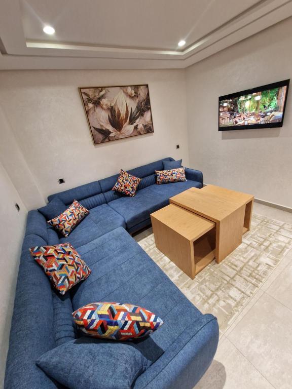 a living room with a blue couch and a wooden table at Hotel Residence Ramsis in Nador