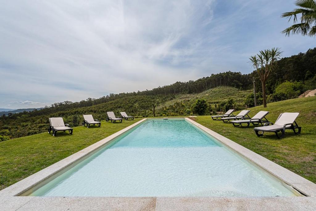 uma piscina com espreguiçadeiras e um grupo em Countryside retreat in Barcelos em Viatodos