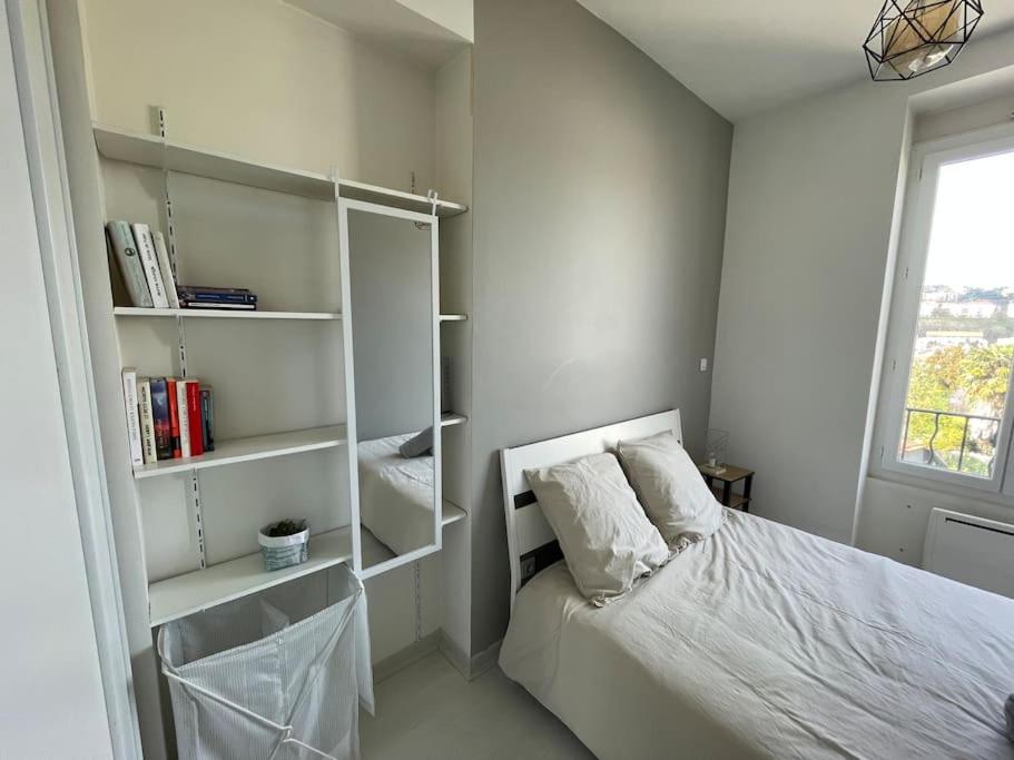 ein Schlafzimmer mit einem Bett, Regalen und einem Fenster in der Unterkunft Appartement T1 proche métro Oullins Centre in Oullins