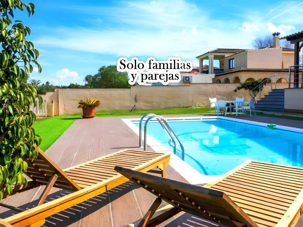 einen Pool mit zwei Stühlen neben einem Haus in der Unterkunft Chalet con Piscina Privada Vistas a Campo de Golf in Chiclana de la Frontera