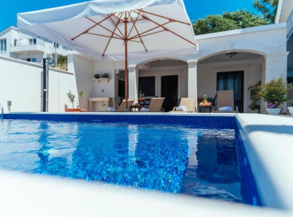 um guarda-chuva branco sentado ao lado de uma piscina em Apartments Trogrlić em Hvar