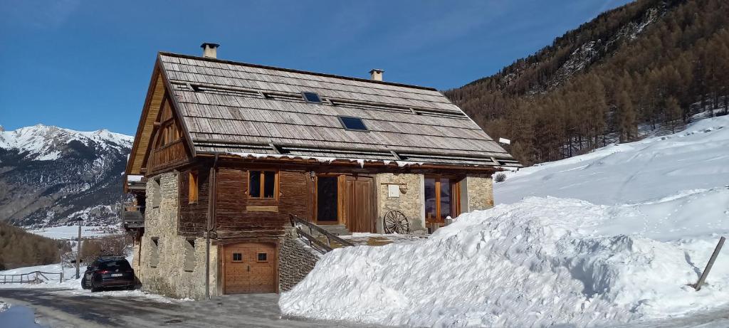 a log cabin in the snow with a pile of snow at Chalet prestige front de neige 14 pers in Ceillac