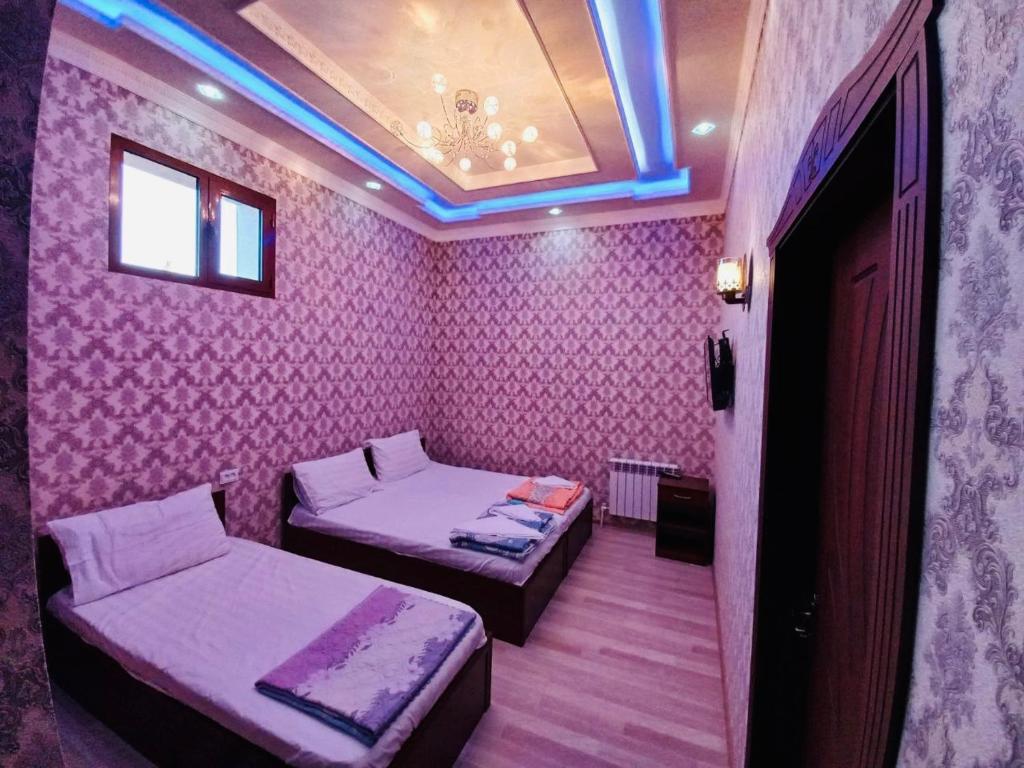 two beds in a room with pink wallpaper at Yusuf Gold House in Samarkand