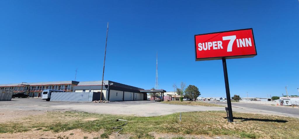 a sign in front of a building with a super minivan at Super 7 Inn in Midland
