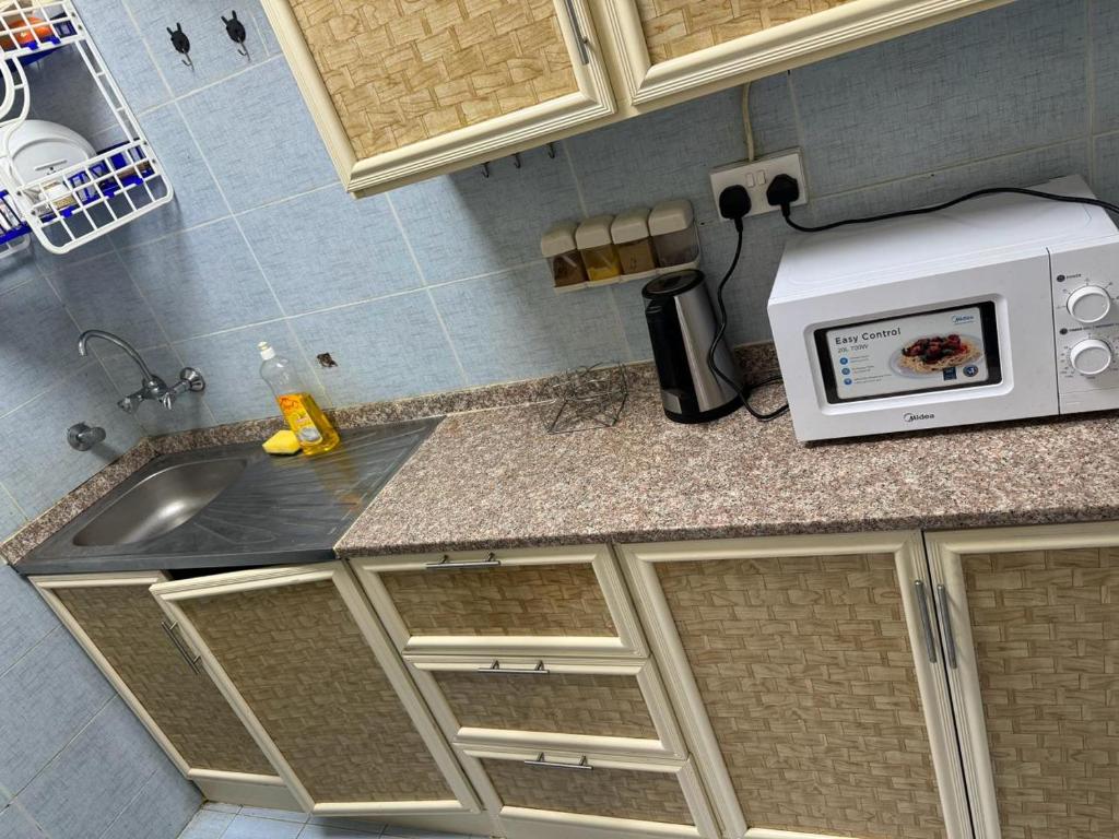 a kitchen with a sink and a microwave at العين الهيلي مصباح ب 8 in Al Ain