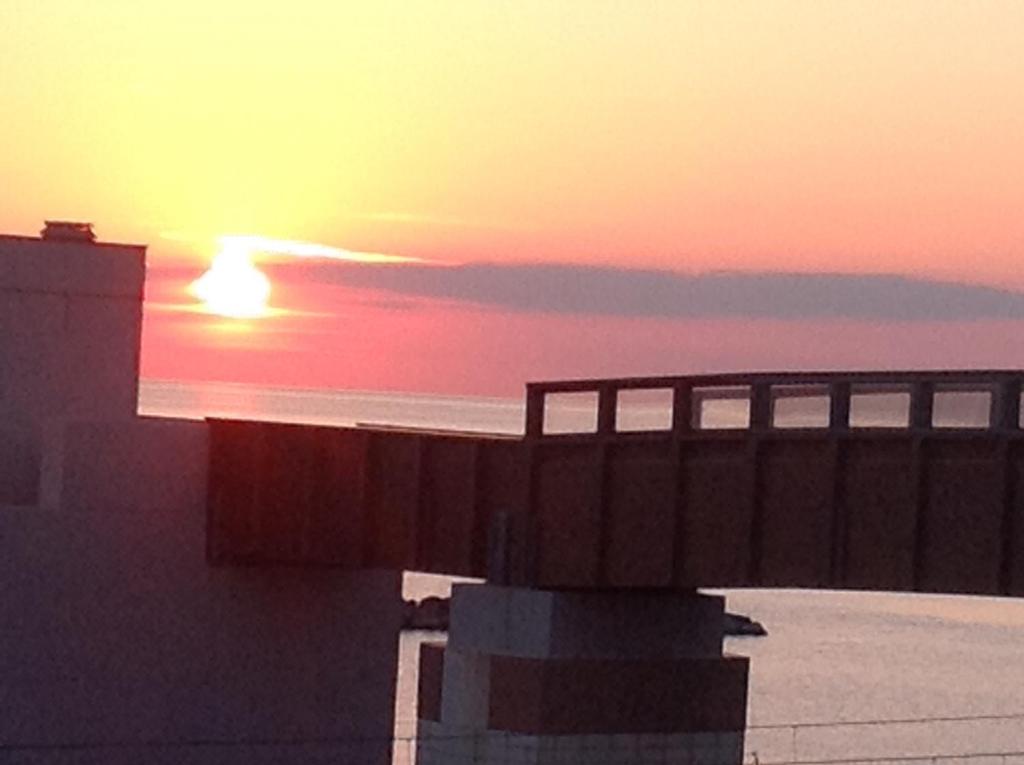 einen Sonnenuntergang über dem Meer mit einer Brücke und einem Gebäude in der Unterkunft B&B Pontemare in Ancona