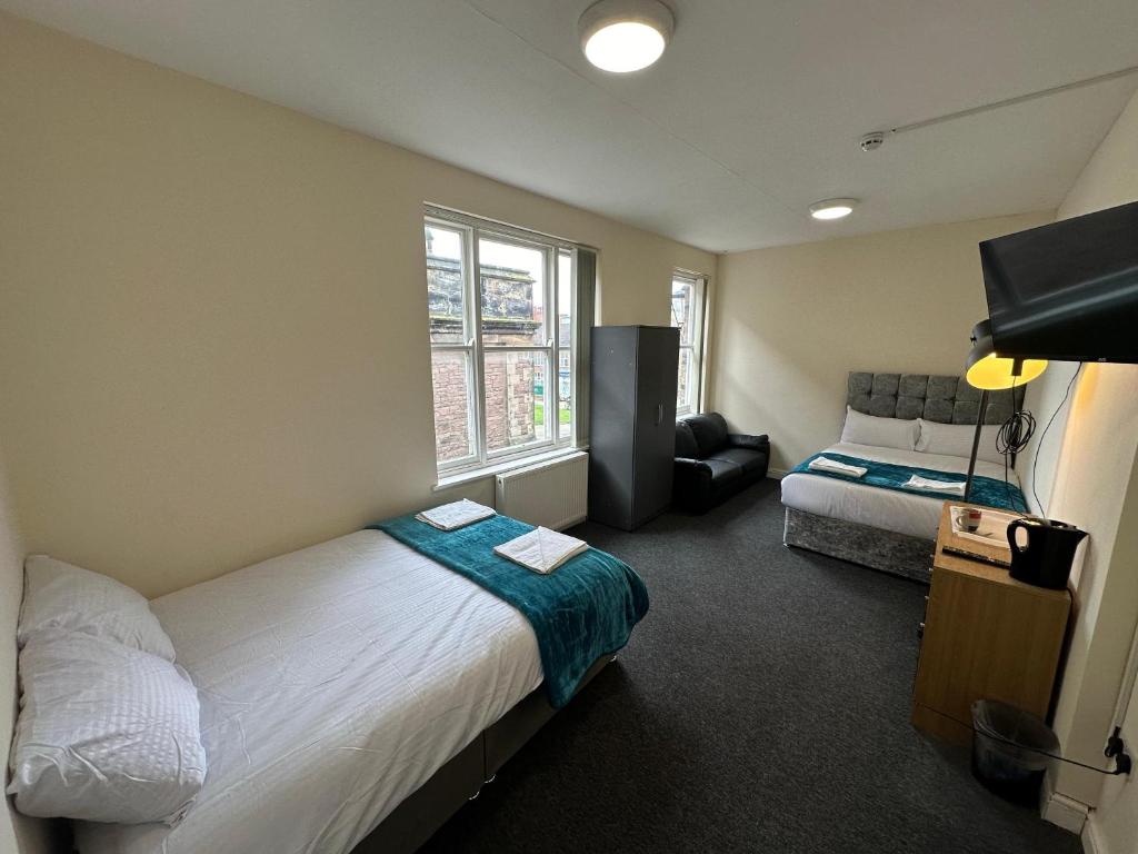 um quarto com 2 camas, um sofá e uma janela em Macclesfield Lodge em Macclesfield