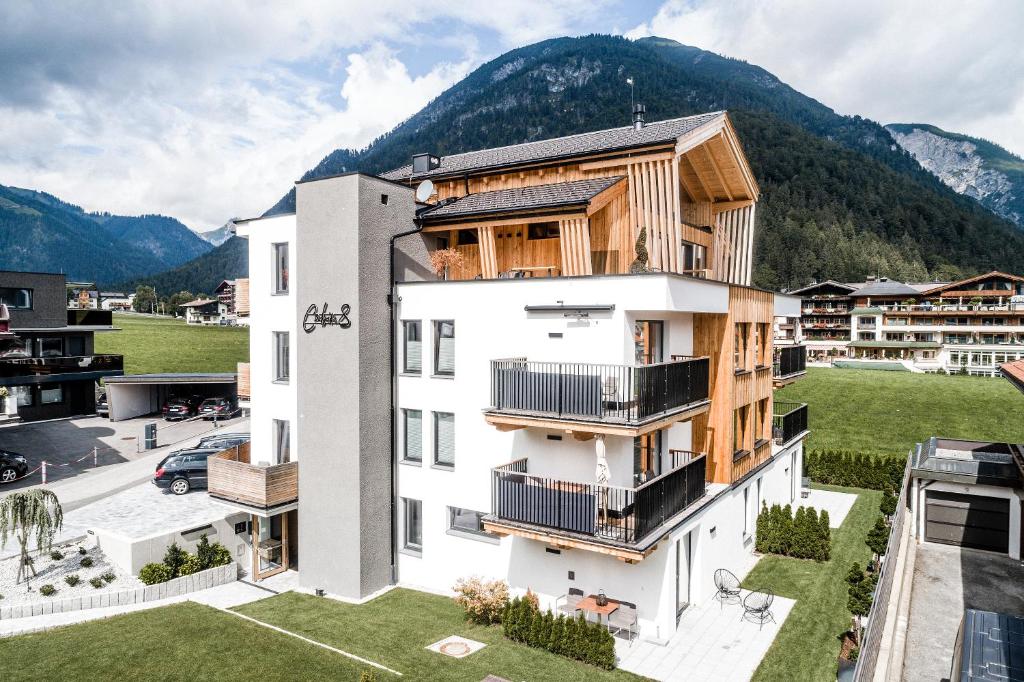 um edifício de apartamentos com varandas de madeira e montanhas ao fundo em Cabin8 Alpine Flair Apartments em Pertisau