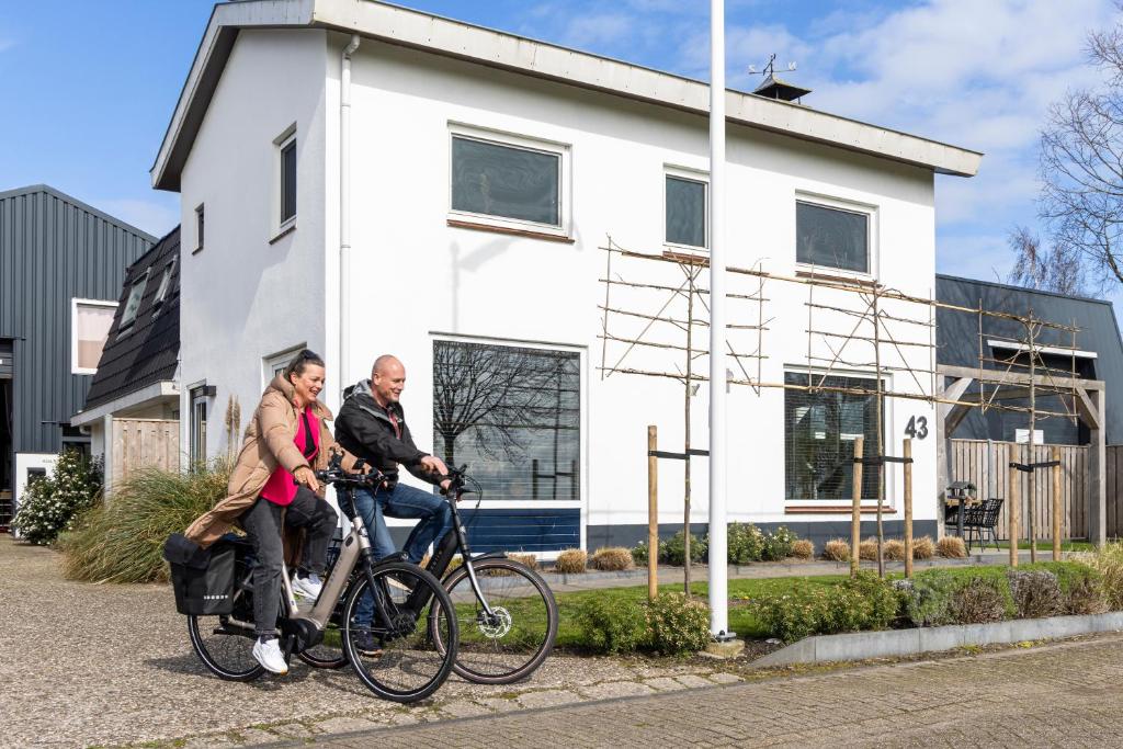 a man and a woman riding bikes in front of a house at Weeruusz in Kolderwolde