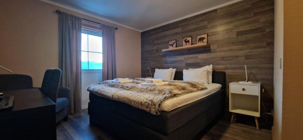 a bedroom with a bed with a wooden accent wall at Kvitfjell Hotel in Strande