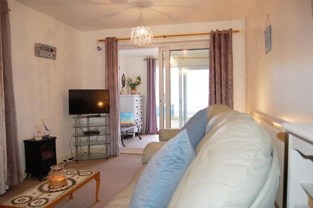 Una sala de estar con un sofá y un televisor. en Seagull Beach House, en Tywyn