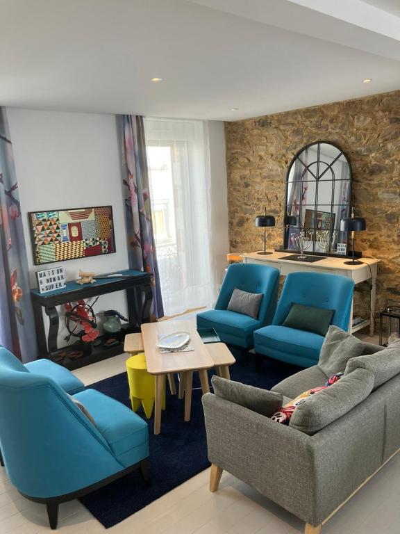 un salon avec des canapés bleus et une table dans l'établissement GITE Maison Nomah Maison haut standing proche plages, classé 5*, à Plouha